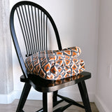 Block print velvet blanket. Tan background with blue and gold diamond shapes, folded on a black chair.