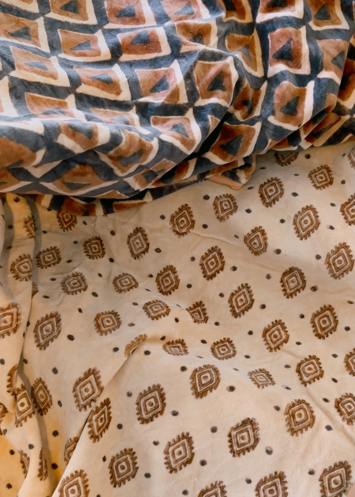 Block print velvet blanket. Tan background with brown diamond print. Reversible print has blue and gold diamond shapes
