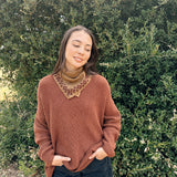 Floral printed bandana tied around the neck, styled with an orange brown sweater