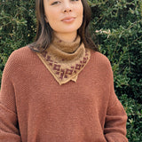Floral printed bandana tied around the neck, styled with an orange brown sweater