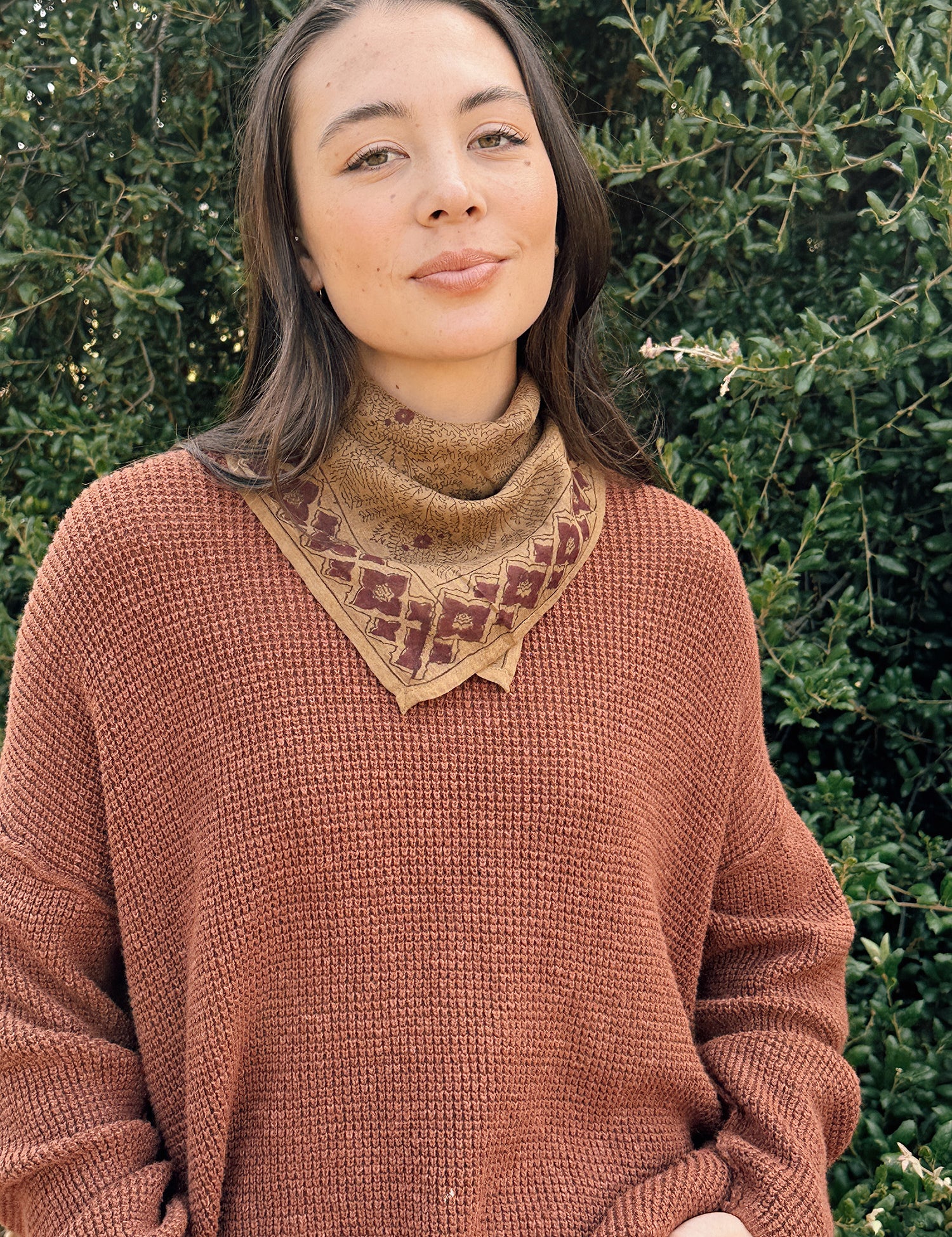 Floral printed bandana tied around the neck, styled with an orange brown sweater