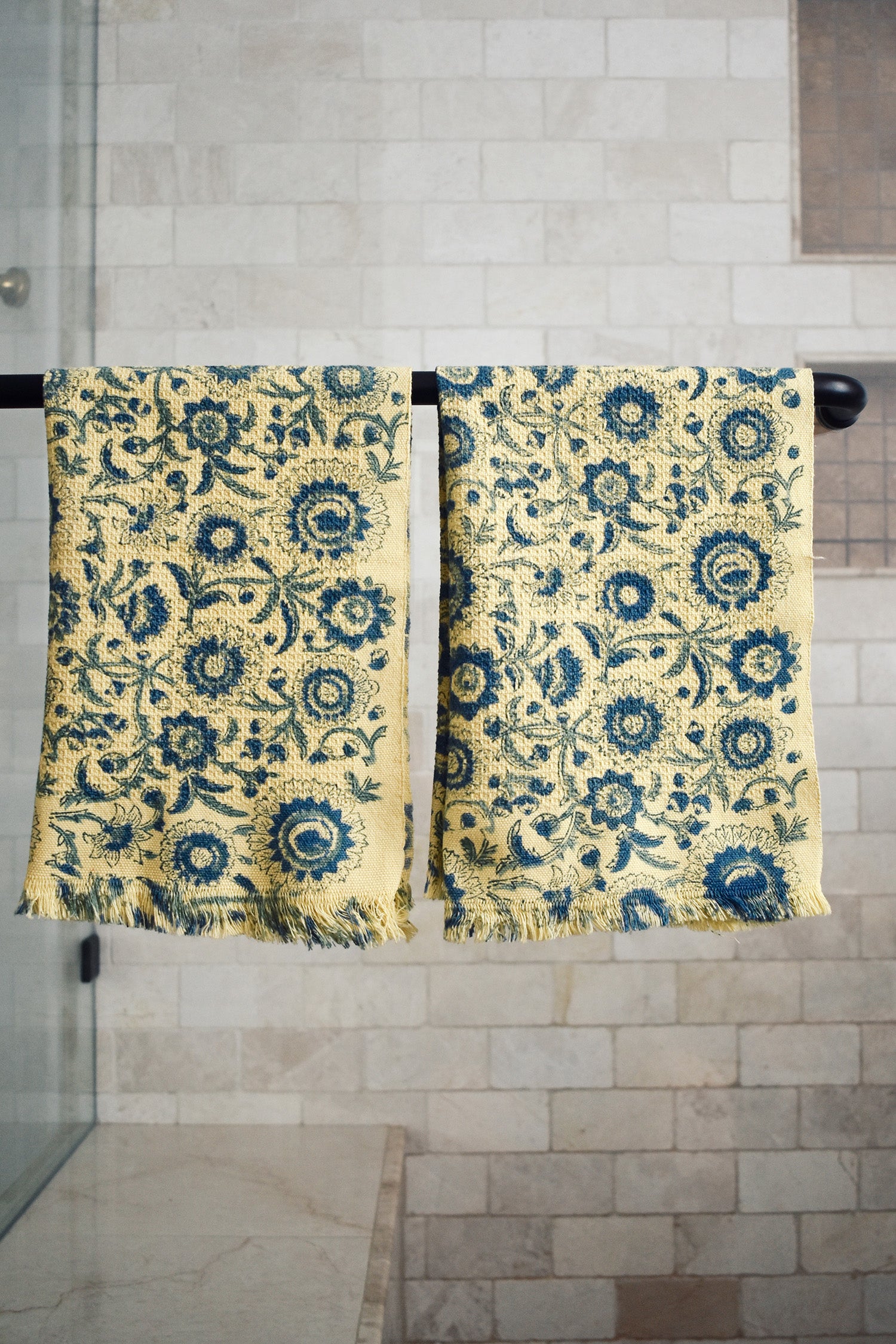 Block printed tropic inspired floral print waffle weave khadi hand towels hanging on a shower rod