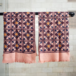 Block printed geometric diamond printed waffle weave khadi hand towels hanging on a shower rod