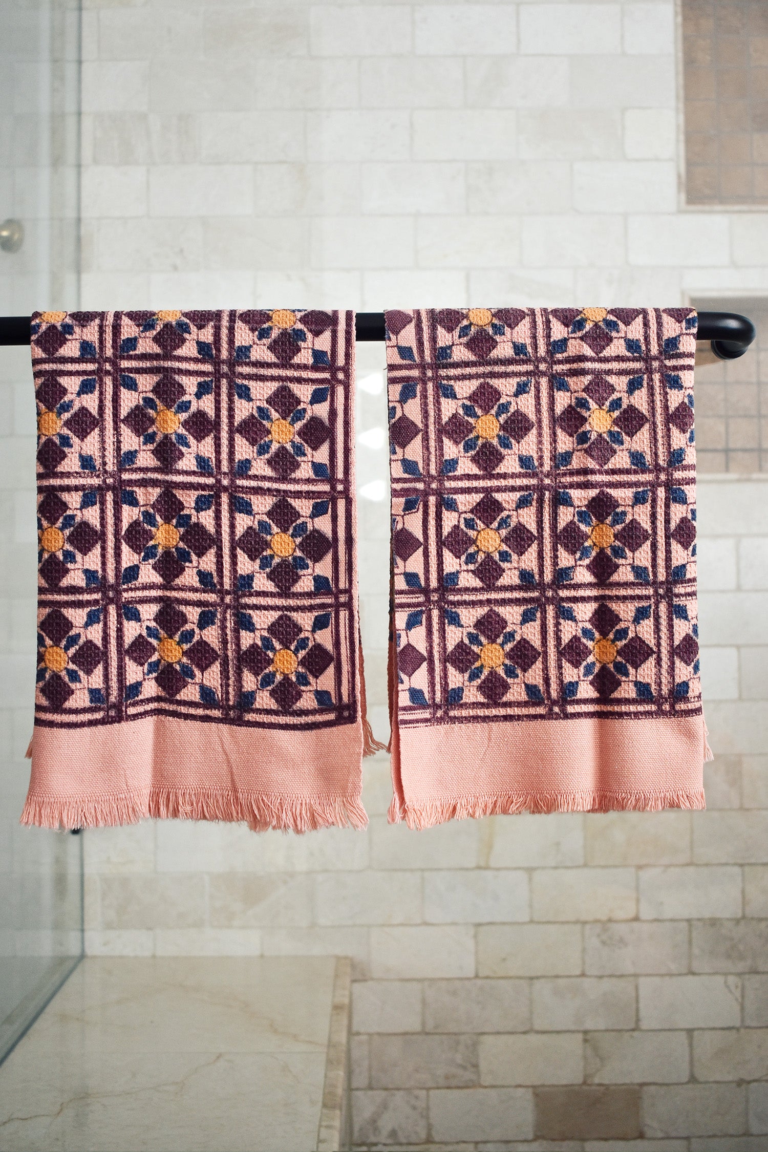 Block printed geometric diamond printed waffle weave khadi hand towels hanging on a shower rod