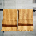Block printed Feliz hand towels hanging on a black rod outside a shower