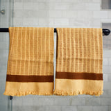 Block printed Feliz hand towels hanging on a black rod outside a shower