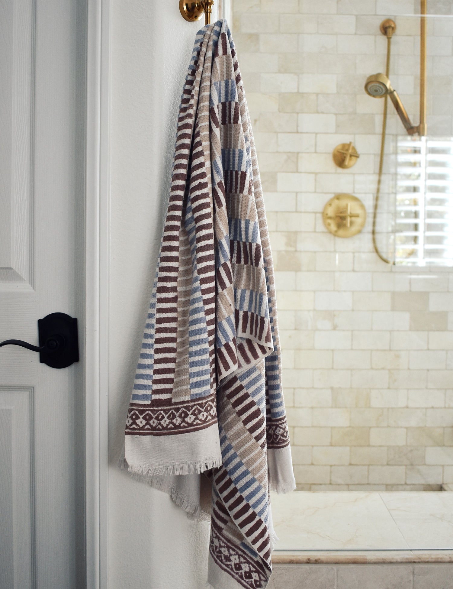 Block printed striped khadi bath towel hanging on a shower hook