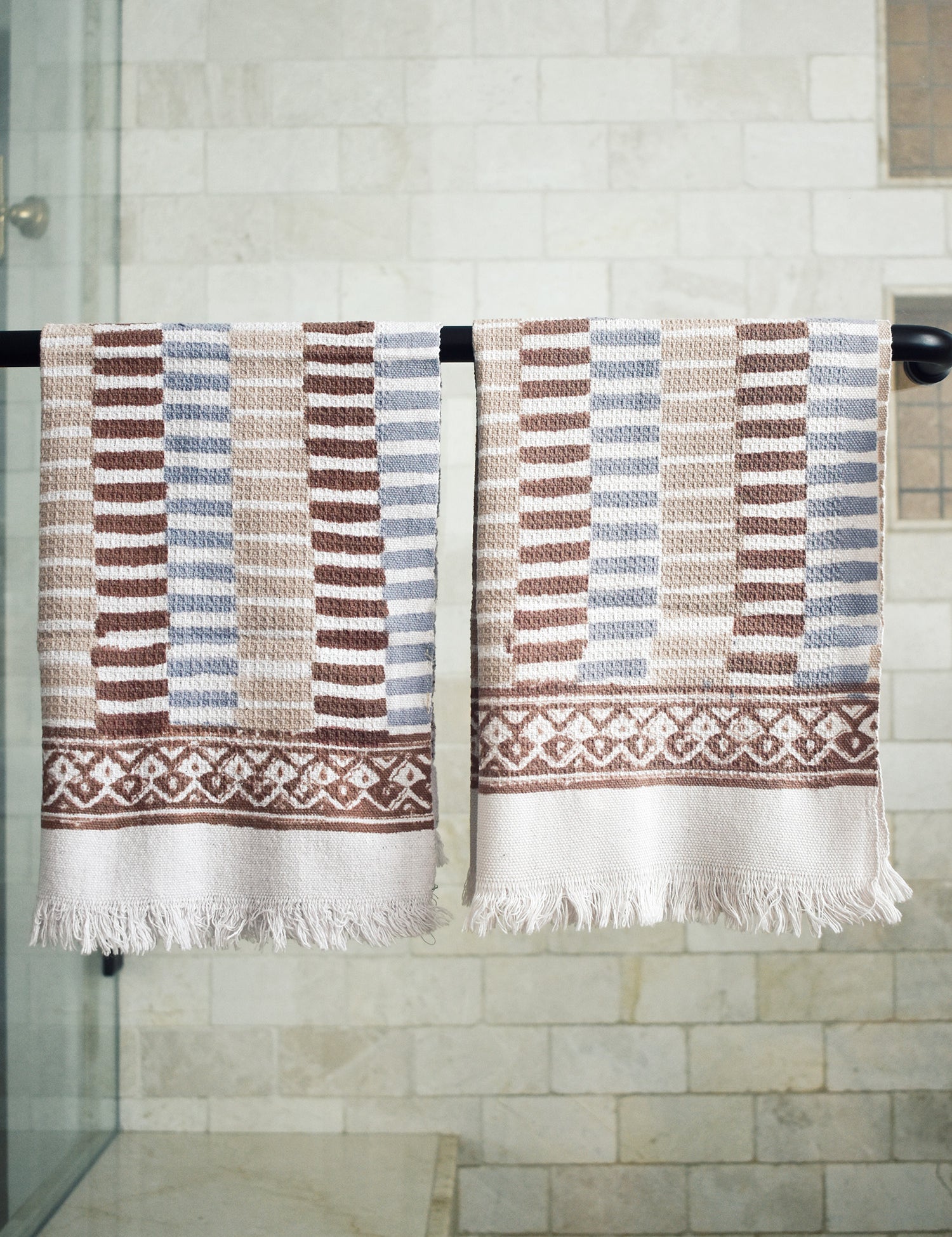 Block printed striped waffle weave khadi hand towels hanging on a shower rod