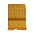 Block printed, yellow/brown, dash/line print bath towel, folded and laid flat against a white background