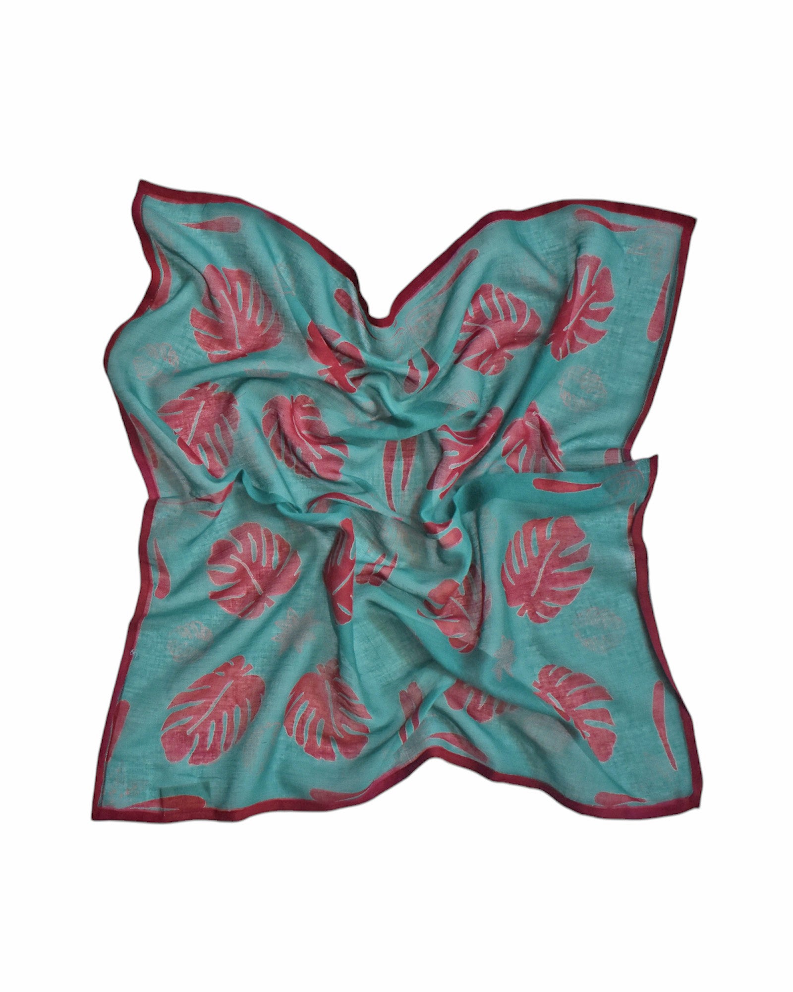 Block printed Monstera bandana, laid flat and scrunched up. Bandana has a red leaf print.