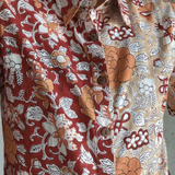 Close-up of a person wearing a patterned shirt with floral and abstract designs.