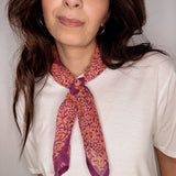 Woman wearing block printed Amber orange and purple bandana around the neck