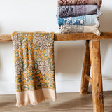 Stack of patterned bath towels on a wooden stool against a white wall