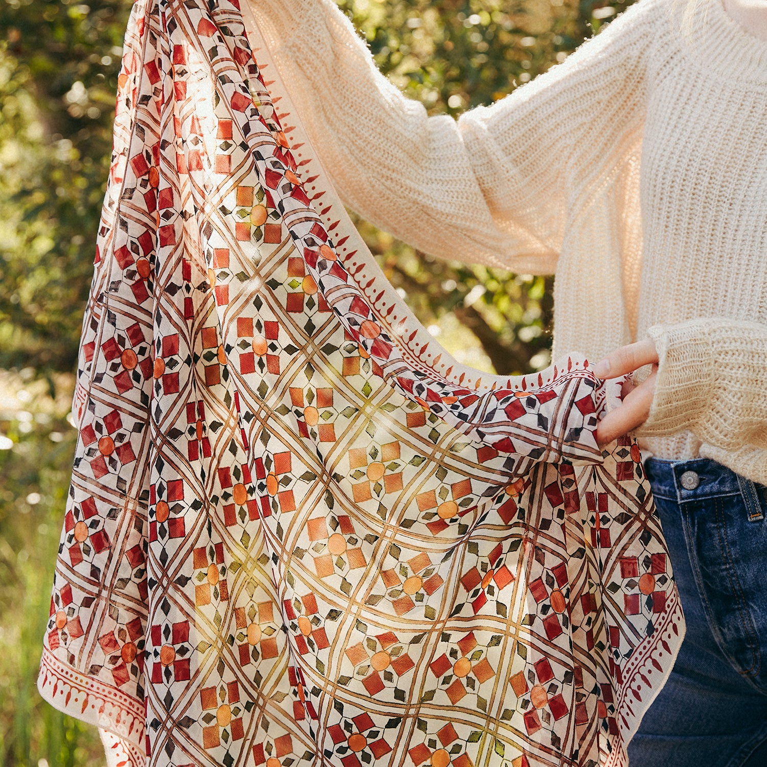 Woman holding up printed scarf