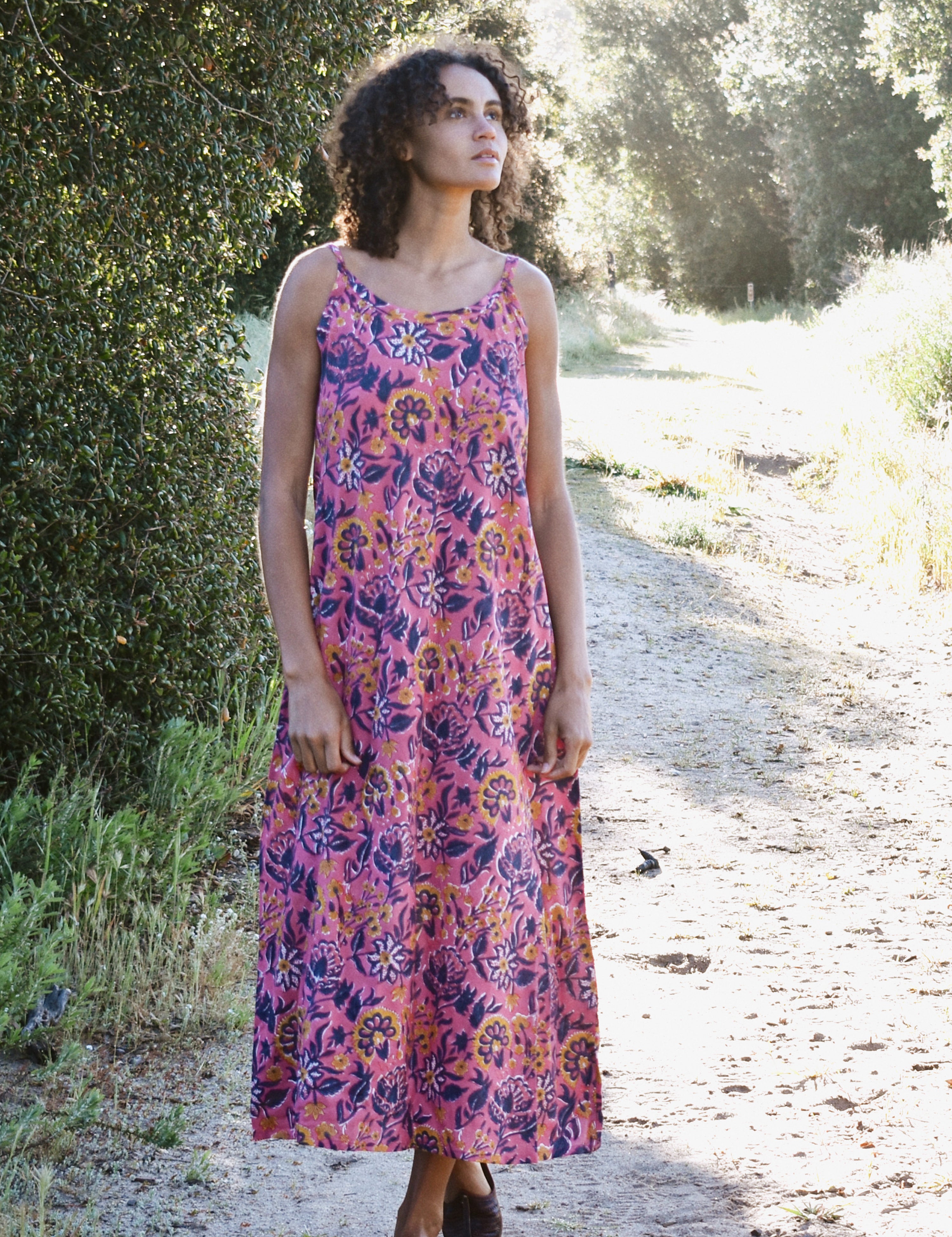 Woman wearing pink and purple floral printed strap maxi dress outside in nature