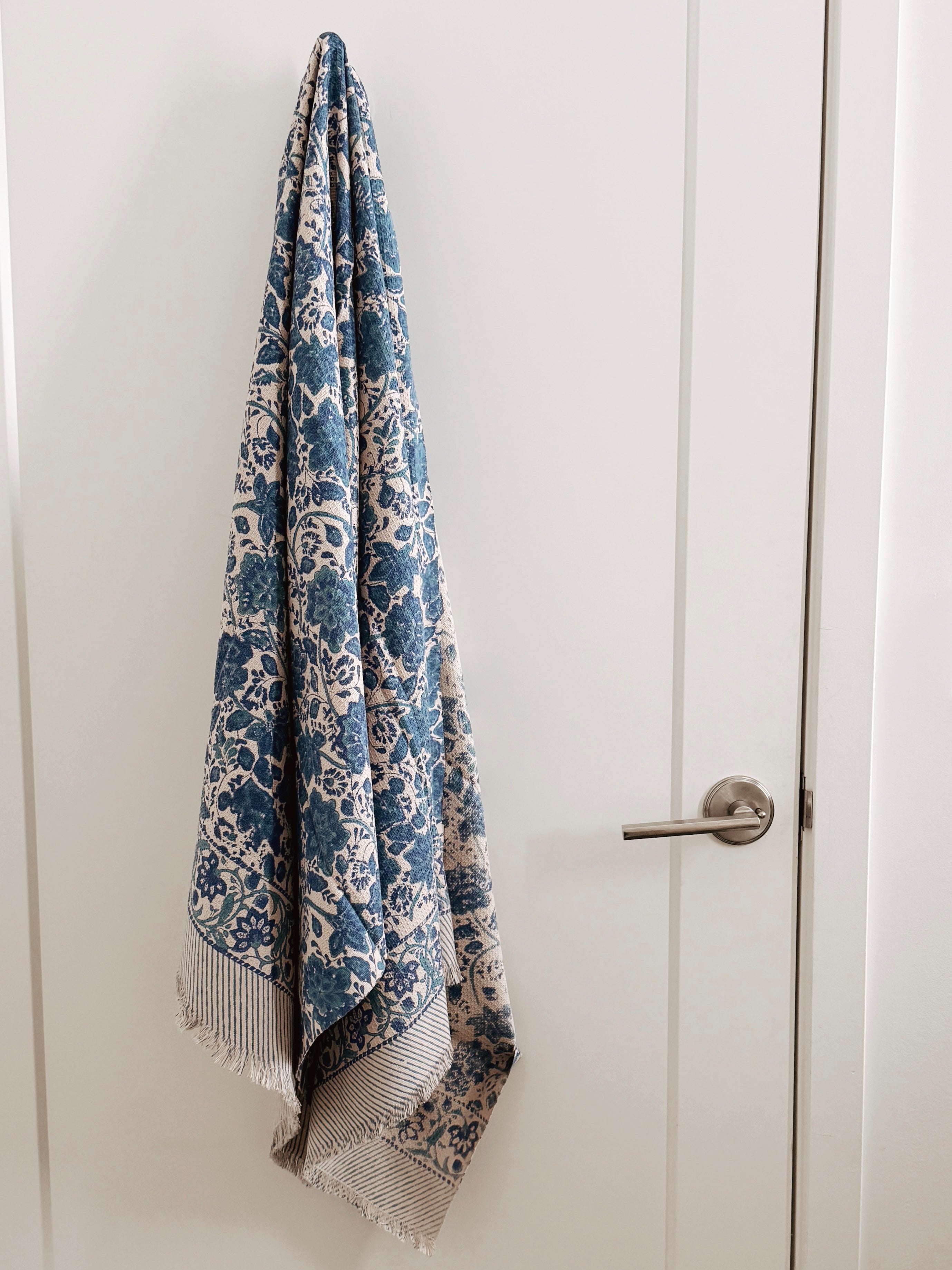 Blue and white floral patterned towel hanging on a white door
