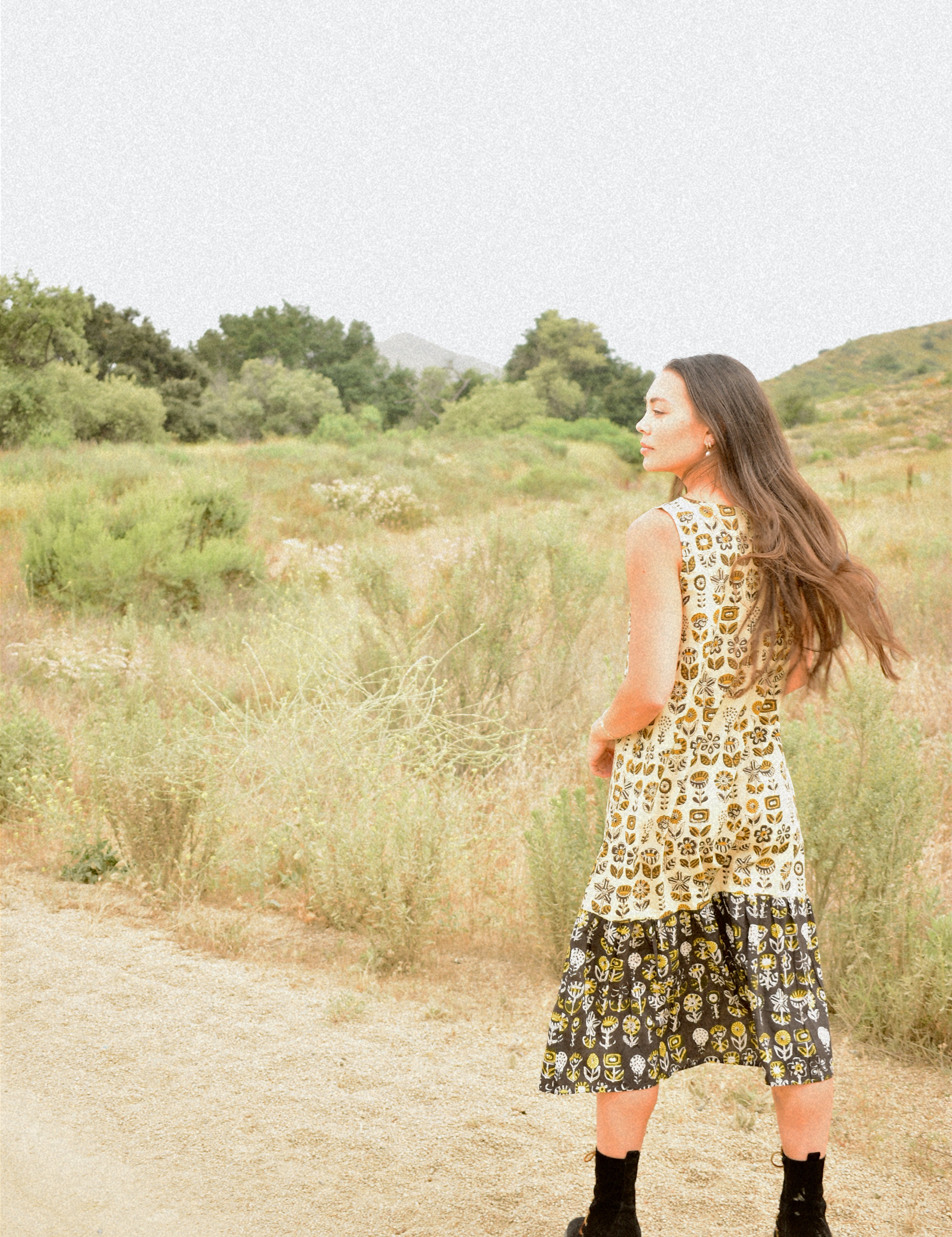 Woman wearing floral block printed sleeveless ruffle dress, back shot