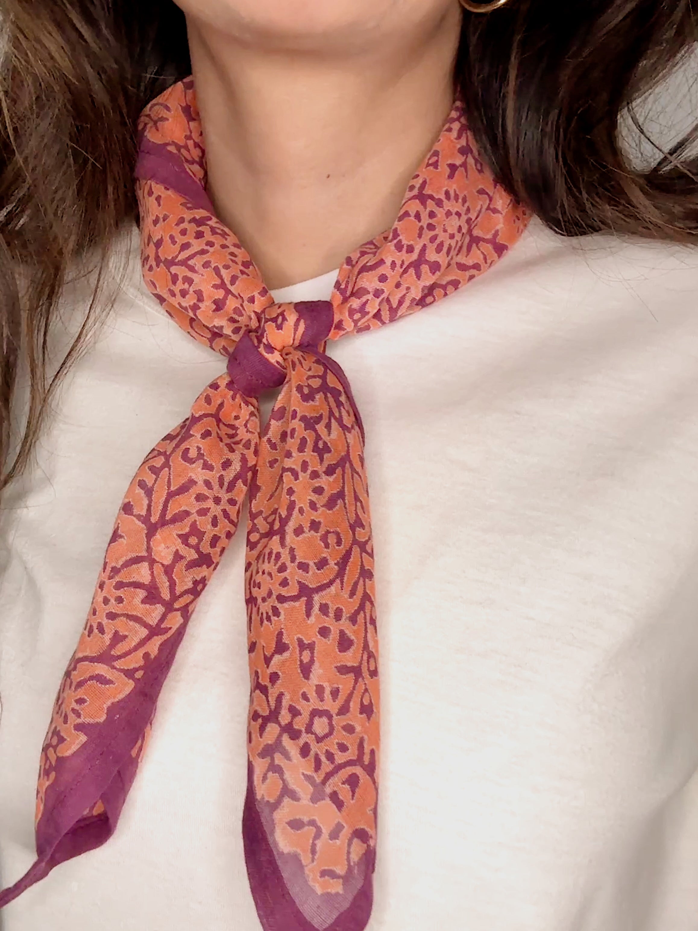 Woman wearing block printed Amber orange and purple bandana around the neck
