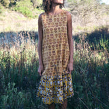 Woman wearing Sharon dress, standing in a field of tall grass. Woman looking up towards the sun.