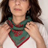 Woman wearing block printed red and green Monstera bandana around the neck