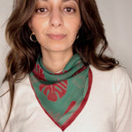 Woman wearing block printed red and green Monstera bandana around the neck