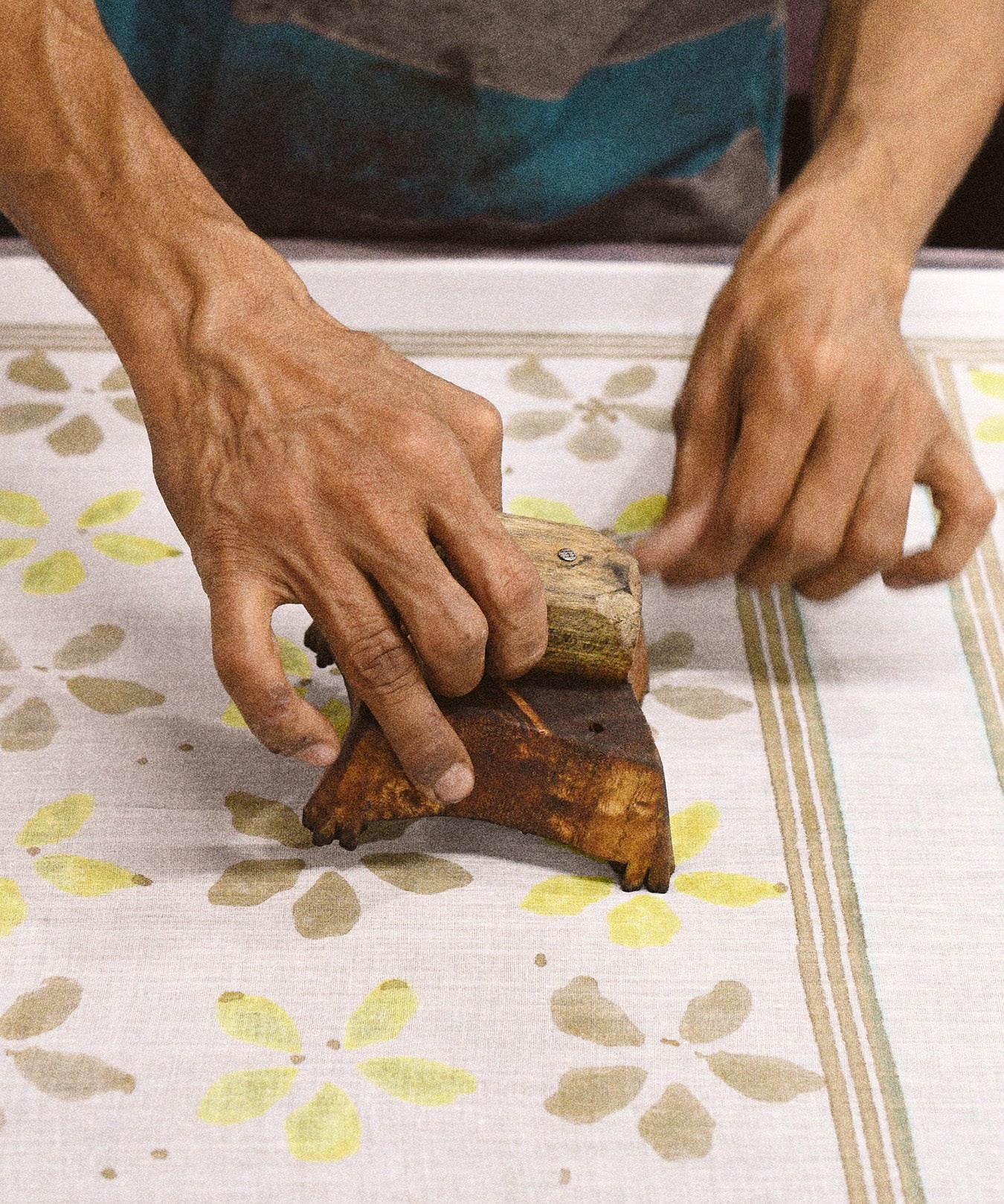 Artist wood block printing flowers onto cotton fabric