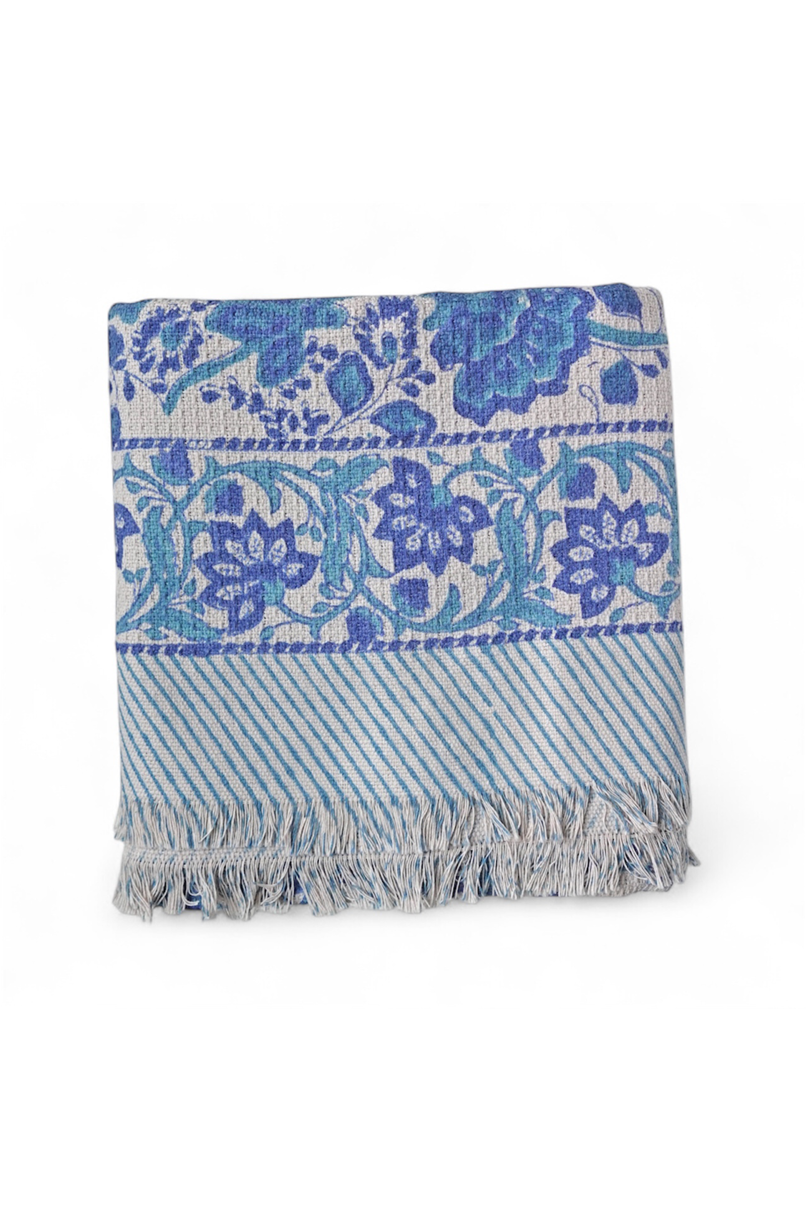 Blue and white patterned bath towel with fringes on a white background
