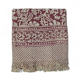 Red floral printed bath towels with intricate pattern and fringes on a white background