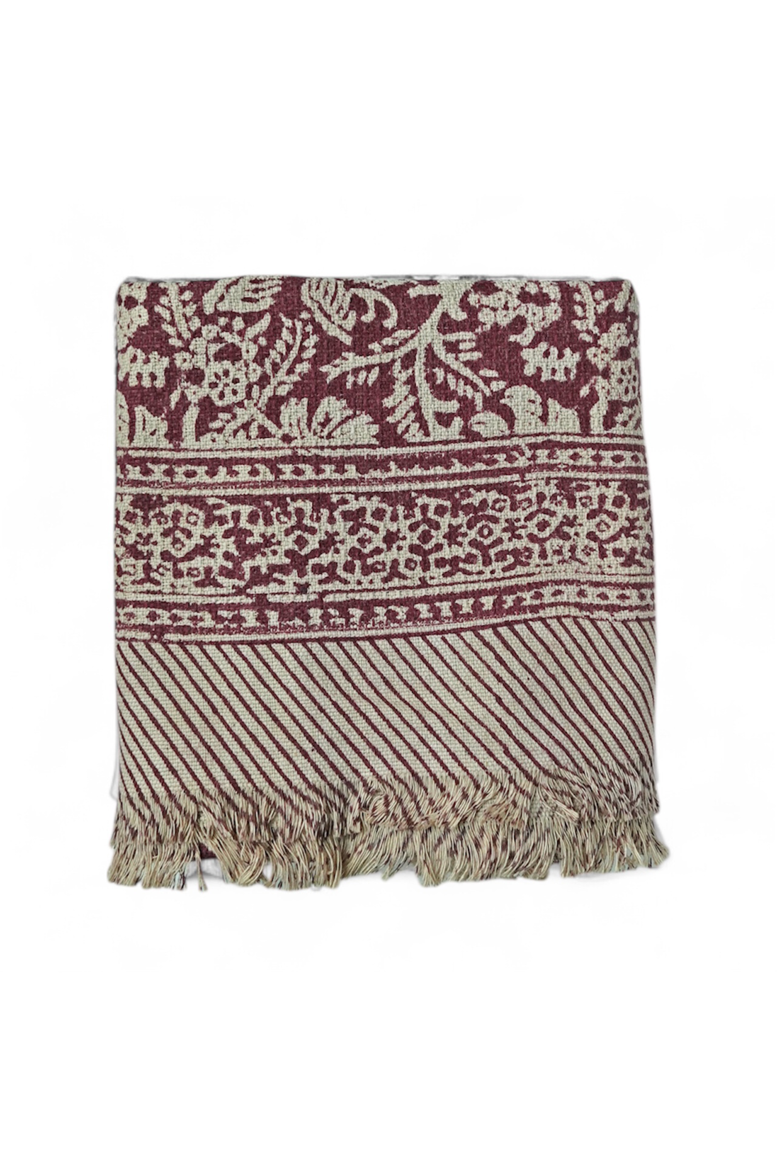 Red floral printed bath towels with intricate pattern and fringes on a white background