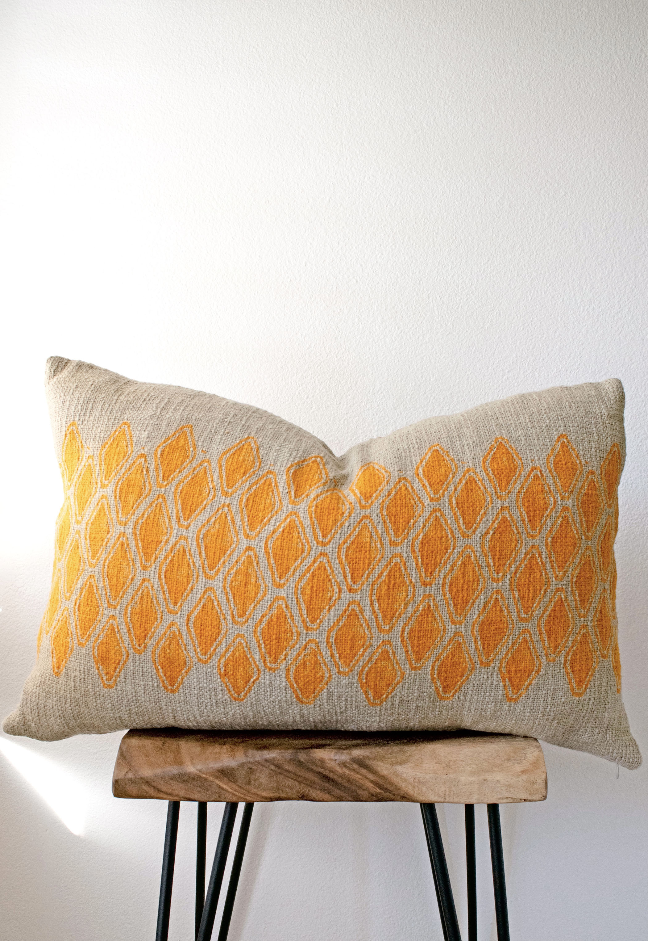 Sol Block Print Pillow on a stool against white