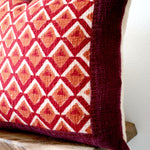 Pitaya block print pillow on a stool against white, angled