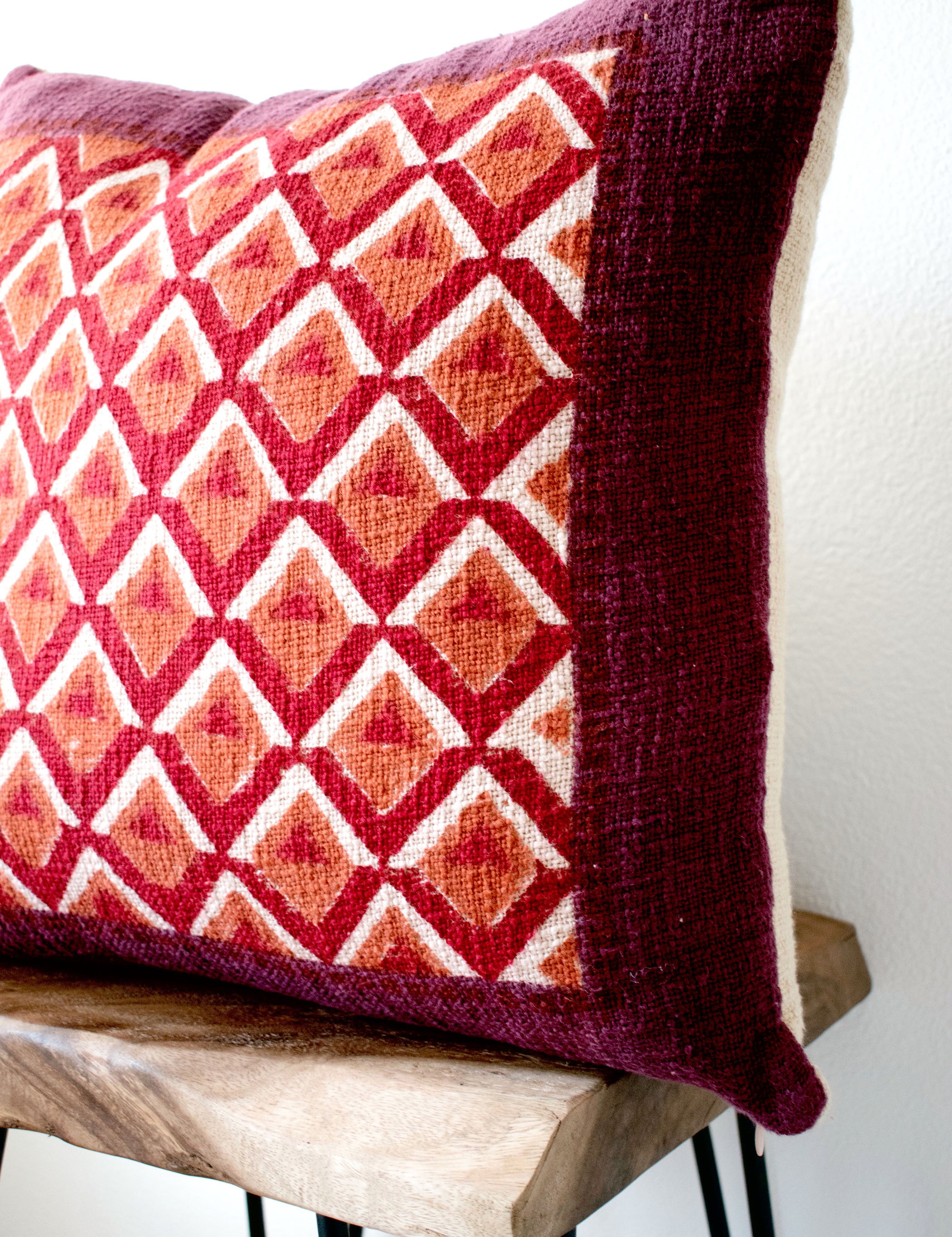 Pitaya block print pillow on a stool against white, angled