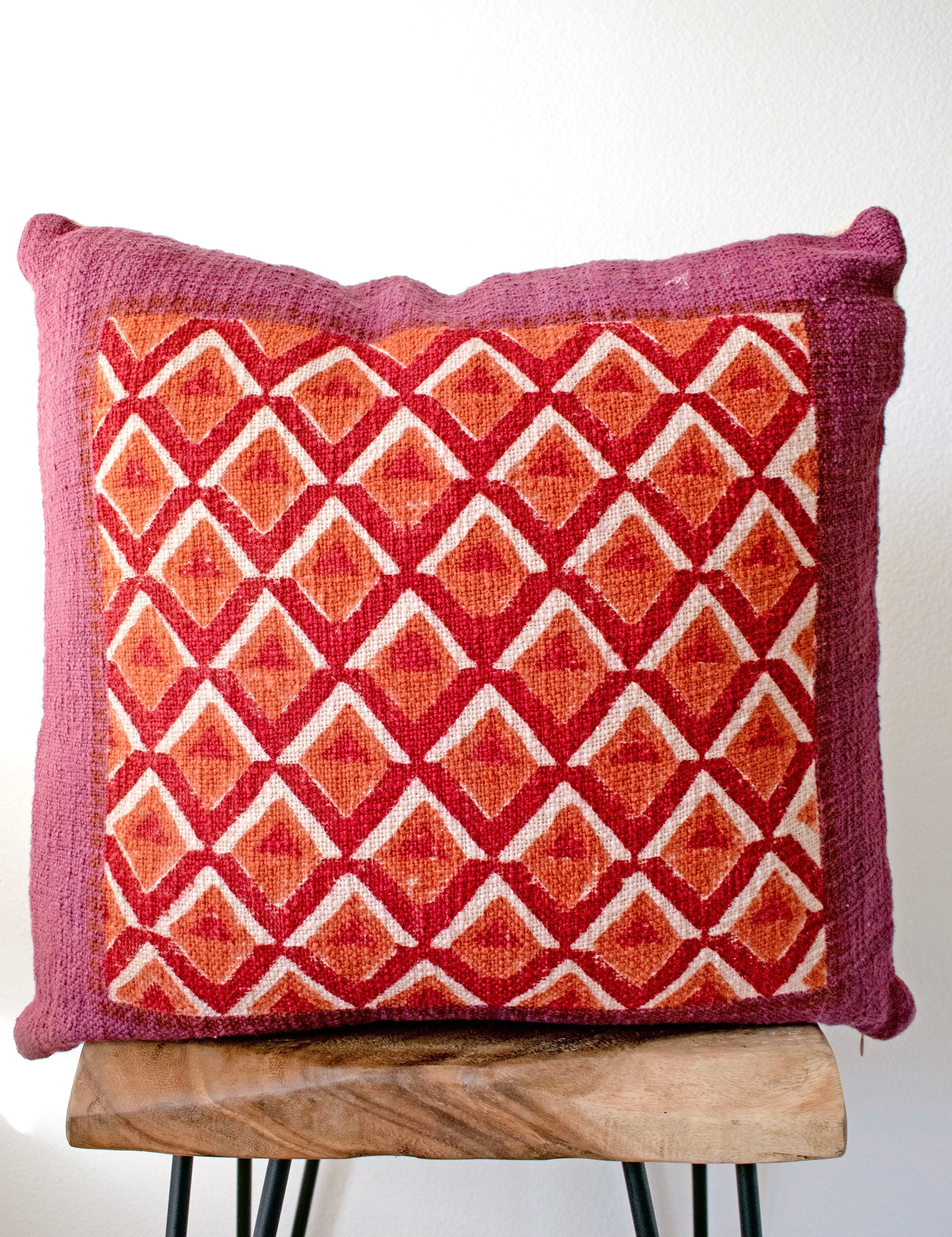 Pitaya block print pillow on a stool against white