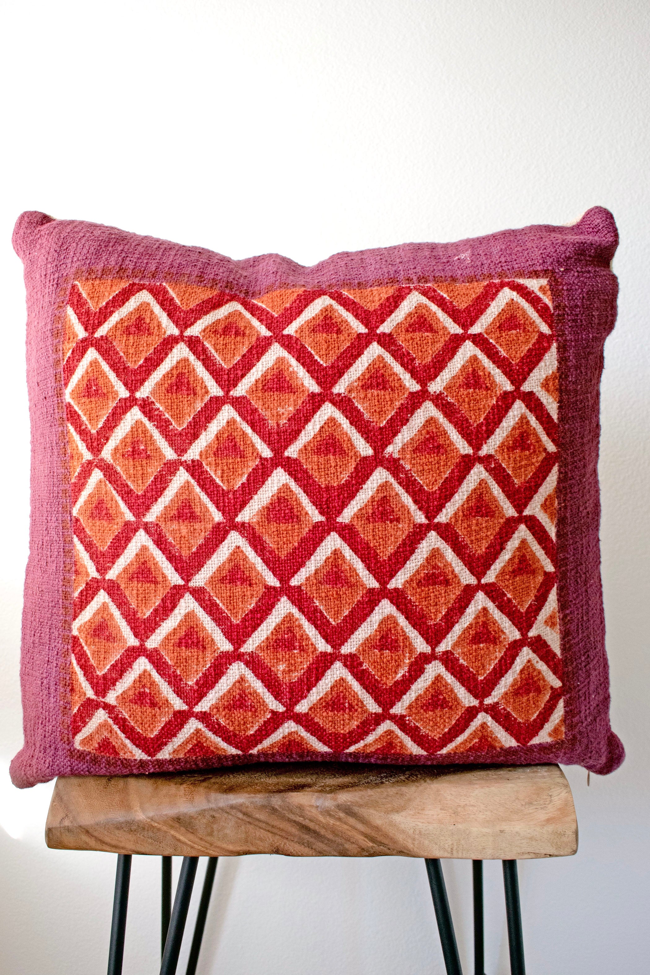 Pitaya block print pillow on a stool against white