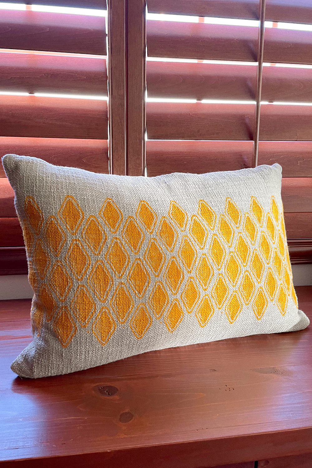 Sol Block Print Pillow on a wooden table, angled