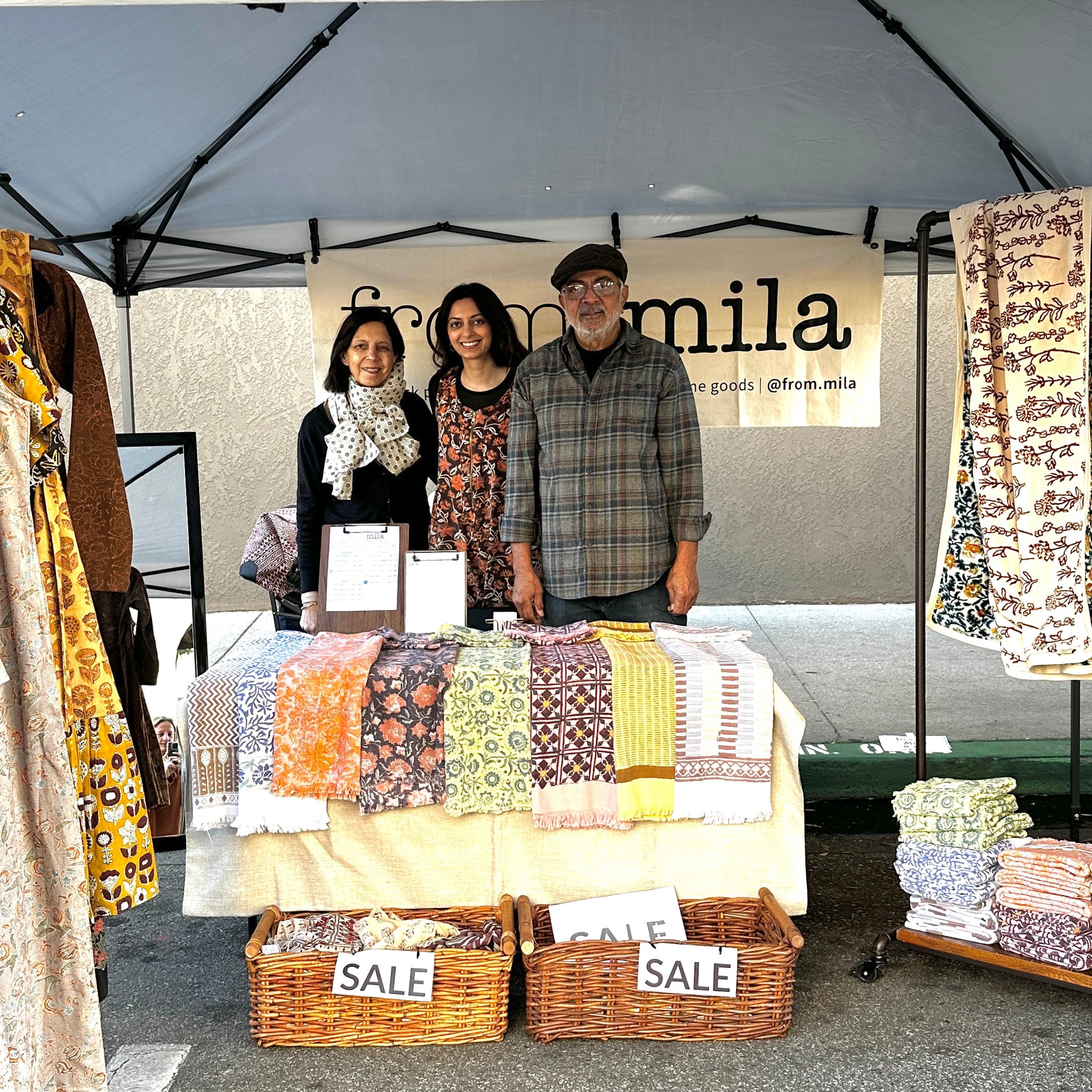 Small Business Saturday, Picture of family in booth behind table filled with towels and sale baskets