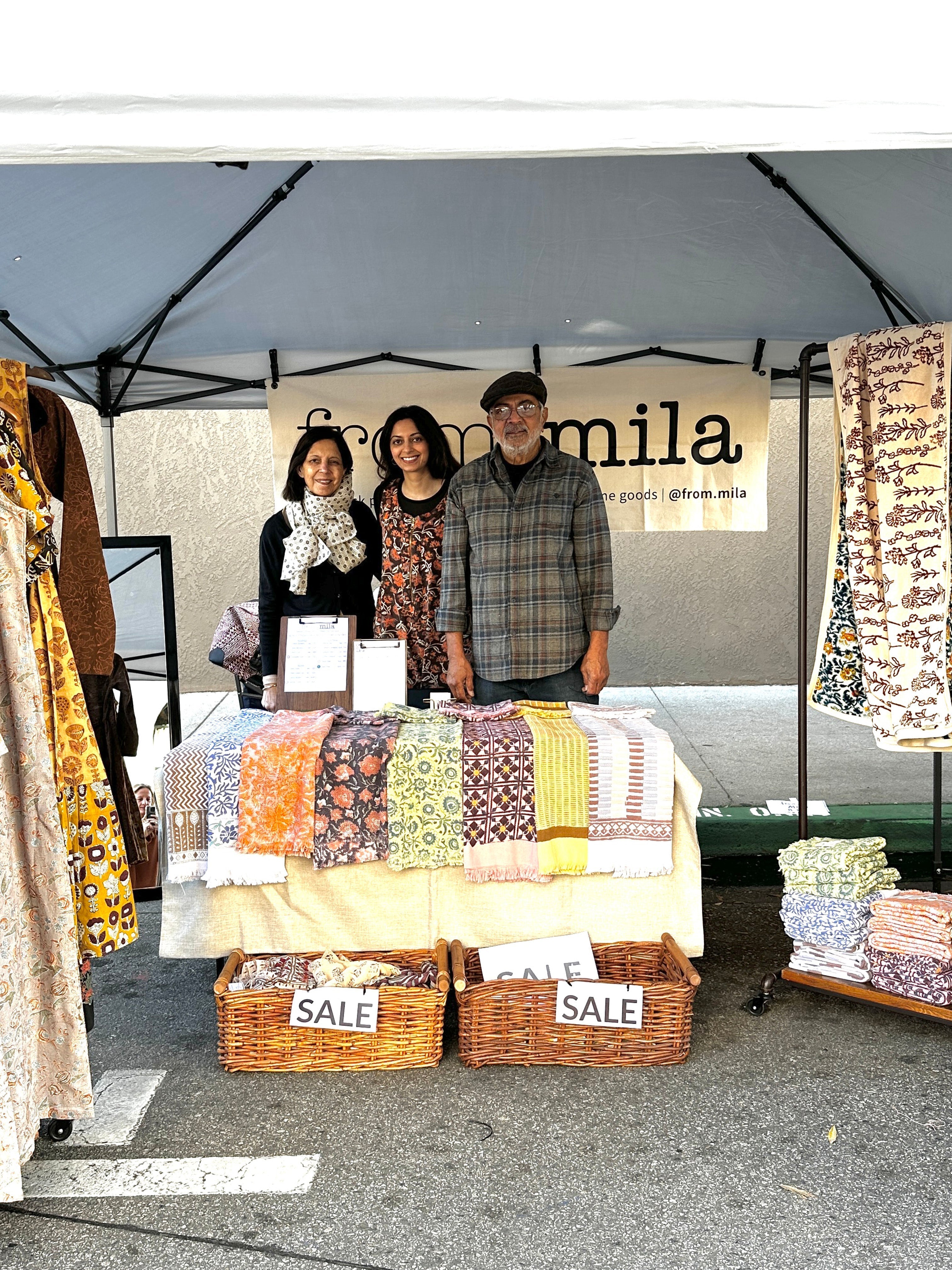 Small Business Saturday, Picture of family in booth behind table filled with towels and sale baskets