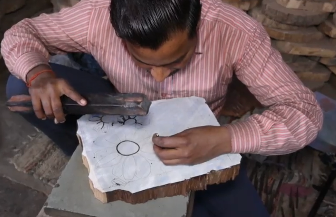 Man hand carving a wooden block with a floral design