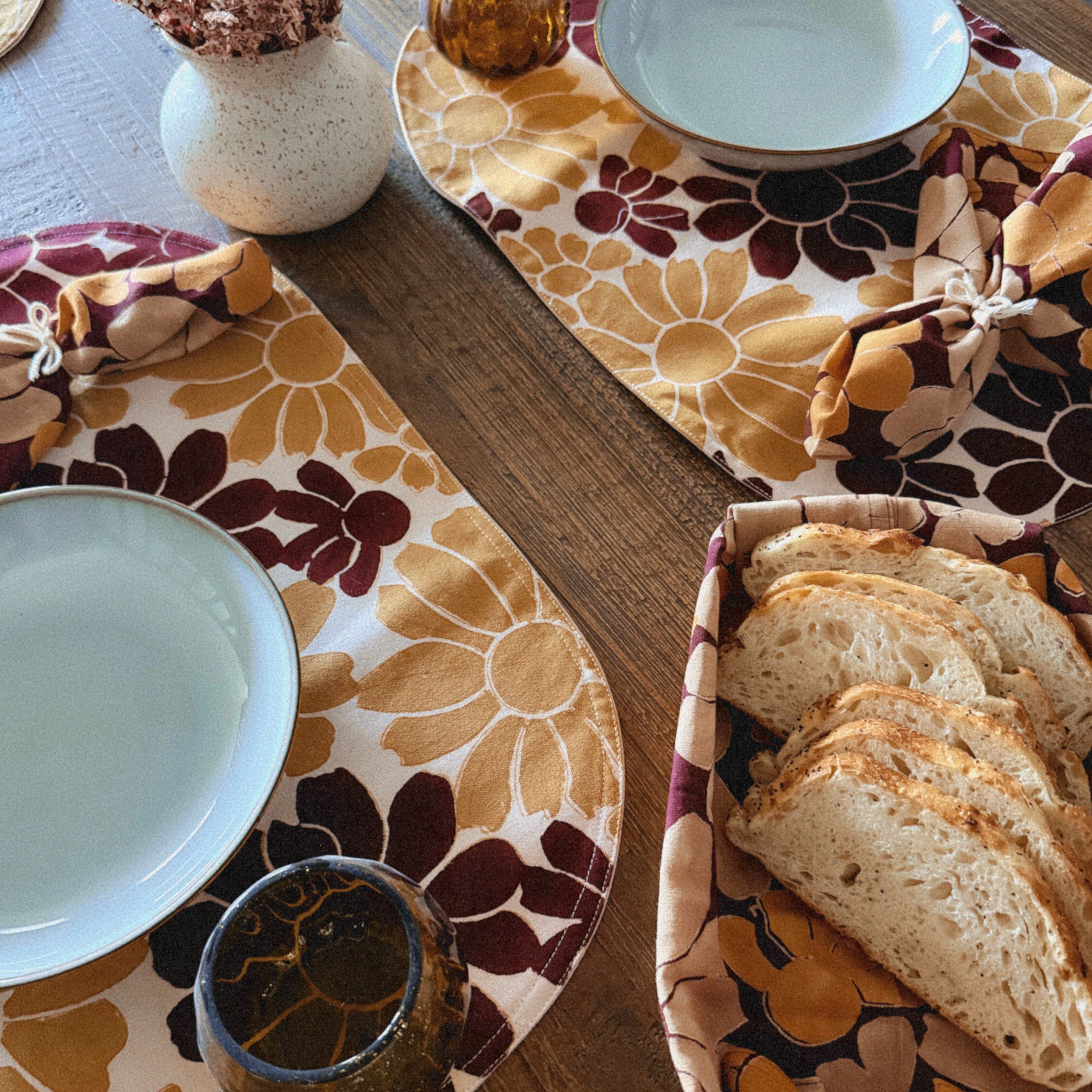 How to romanticize your tablescape and meals at home: Block printed table napkins and matching placemats with floral pattern, table styled with plates, cups and vase of dried flowers