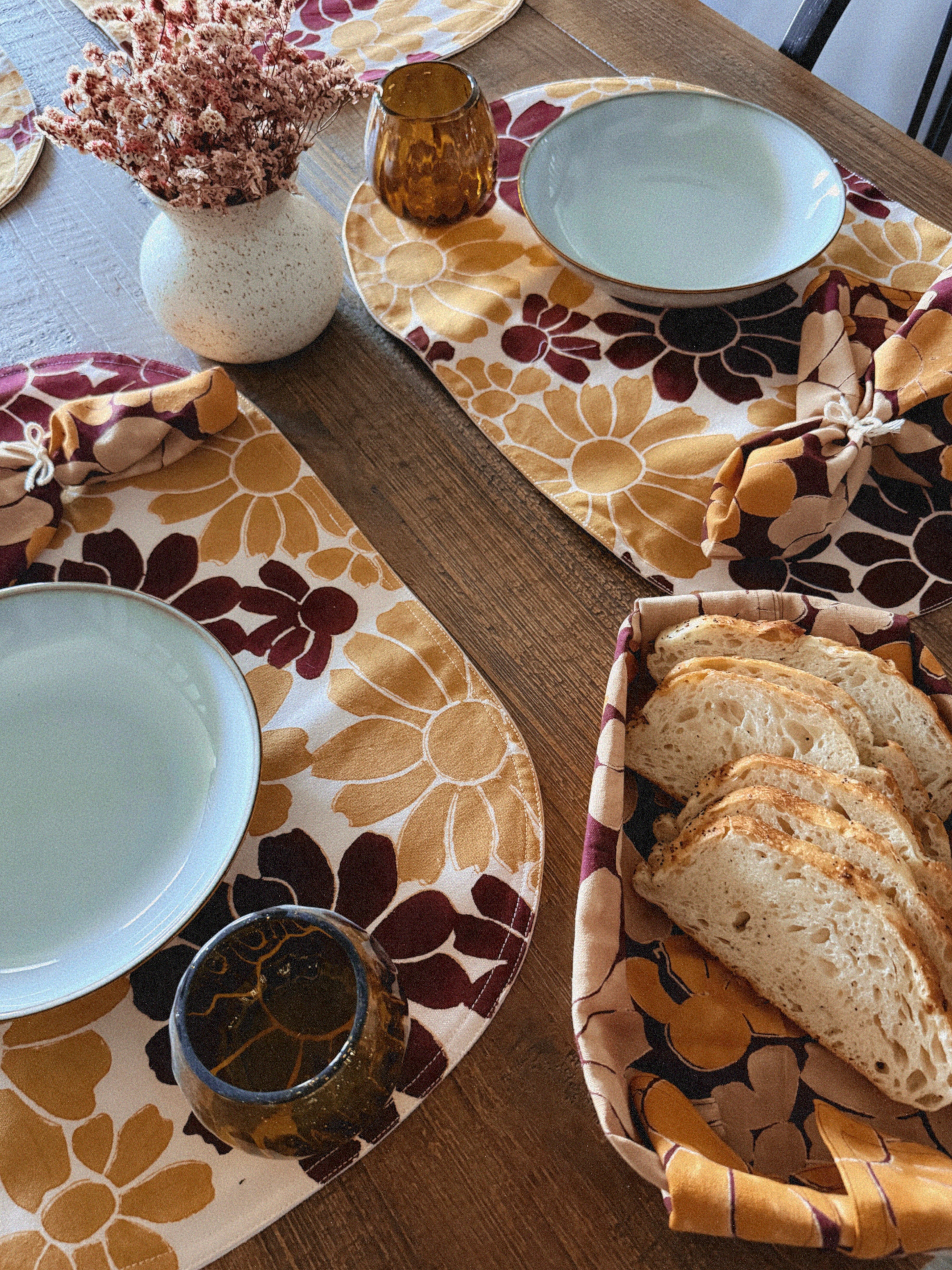 How to romanticize your tablescape and meals at home: Block printed table napkins and matching placemats with floral pattern, table styled with plates, cups and vase of dried flowers