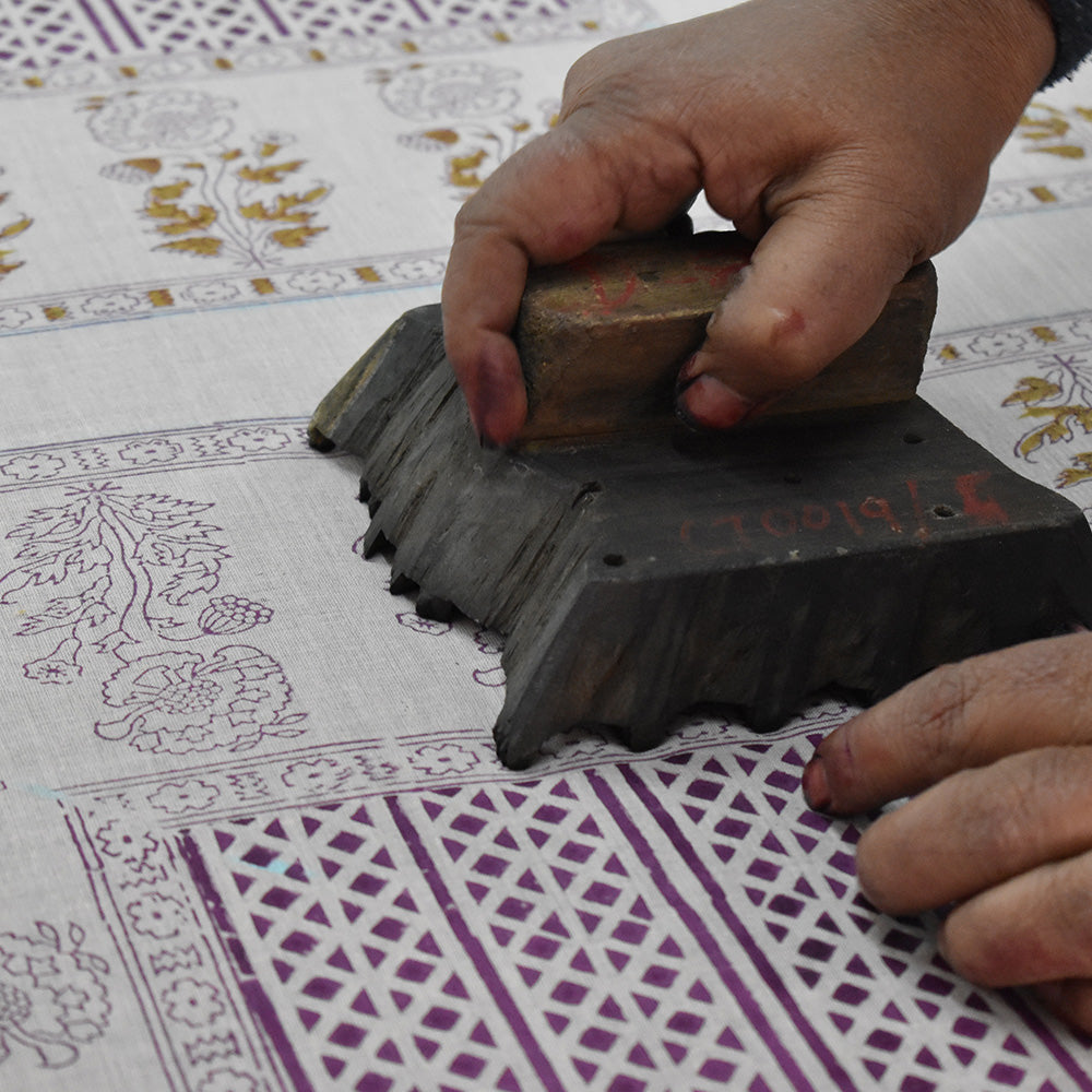 Artist block printing with wooden block onto fabric