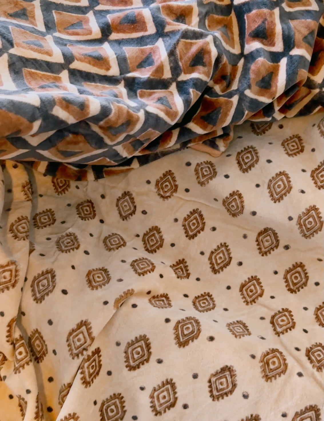 Block print velvet blanket. Tan background with brown diamond print. Reversible print has blue and gold diamond shapes 