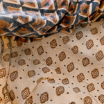 Block print velvet blanket. Tan background with brown diamond print. Reversible print has blue and gold diamond shapes 