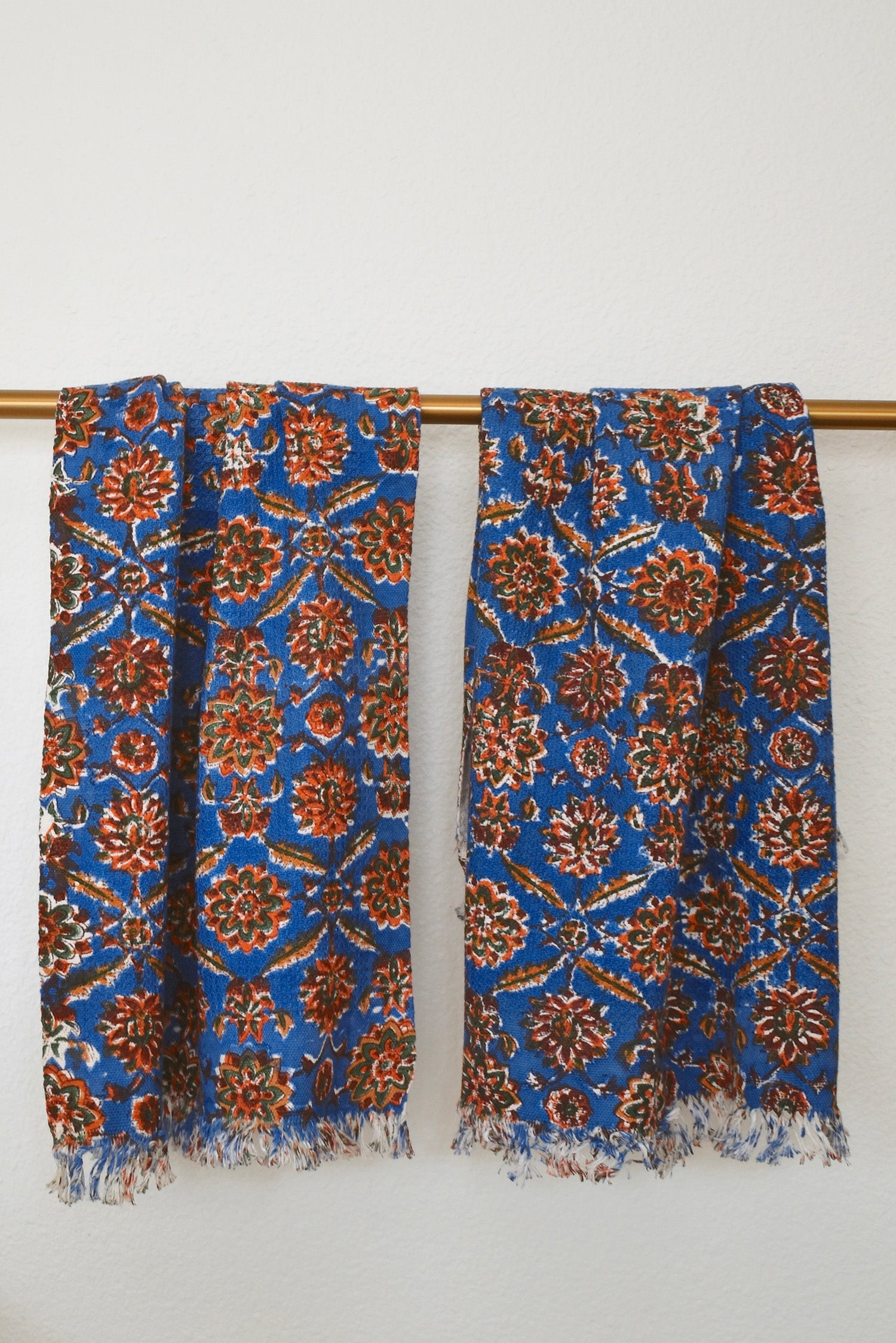 Two Adria block printed khadi cotton hand towels hanging on a gold bathroom rod