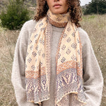 Woman wearing block printed Alice georgette scarf around the neck, paired with tan sweater. Woman is standing outside.