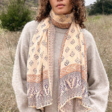 Woman wearing block printed Alice georgette scarf around the neck, paired with tan sweater. Woman is standing outside.