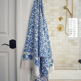 Block printed Athena bath towel hanging on a hook in front of a shower
