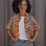 Woman wearing floral printed shirt open with a white tee underneath, paired with jeans 