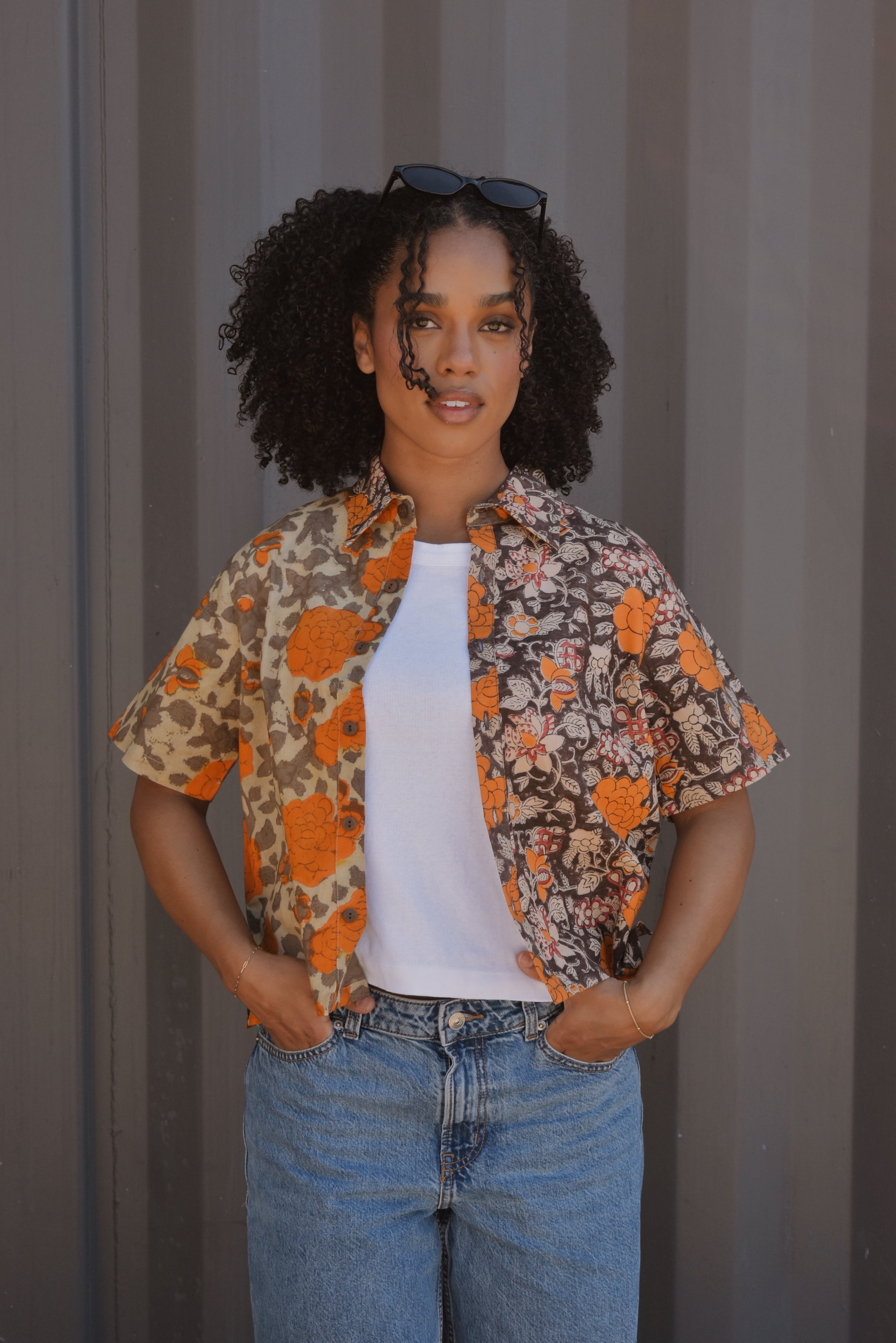 Woman wearing floral printed shirt open with a white tee underneath, paired with jeans 