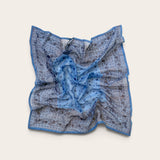 A square scarf with a blue and gray paisley pattern, laid flat on a light beige background.
